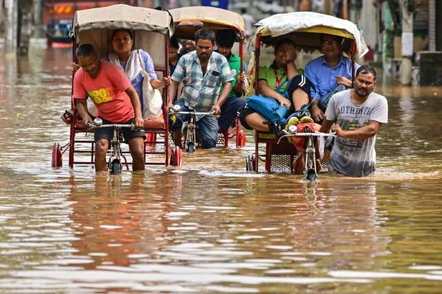 Locals commute in cycle rickshaws as they wade through a flooded street after heavy rains in Guwahati on April 22, 2024. (Photo by Biju Boro/AFP Photo)