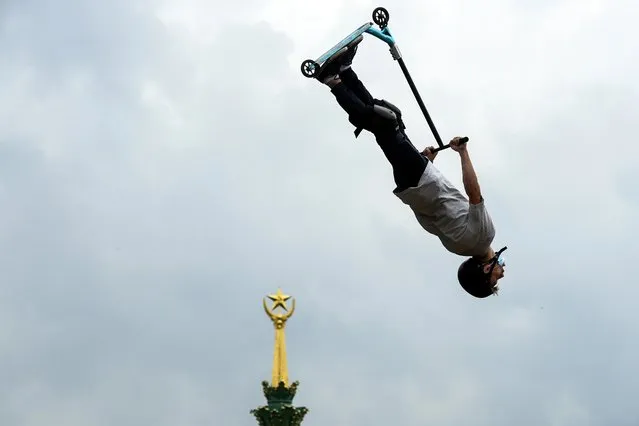 A participant performs a jump with his scooter in front a building with the Soviet Union symbol during a local extreme scooter tournament at the All-Russia Exhibition Centre (VDNKh), a trade show and amusement park in Moscow on August 1, 2020. (Photo by Kirill Kudryavtsev/AFP Photo)