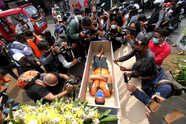 A man, caught not wearing a face mask in public amid the COVID-19 coronavirus pandemic, lies in a mock coffin while members of the public and the media take pictures as part of punishment by local authorities and enforced by local police, in Jakarta, on September 3, 2020. (Photo by Fahmi Dolli/AFP Photo)