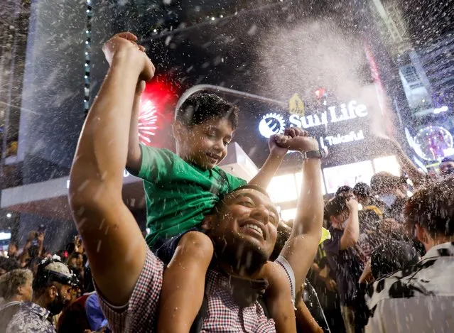 A man celebrates New Year's Eve with a kid in Kuala Lumpur, Malaysia on January 1, 2023. (Photo by Hasnoor Hussain/Reuters)