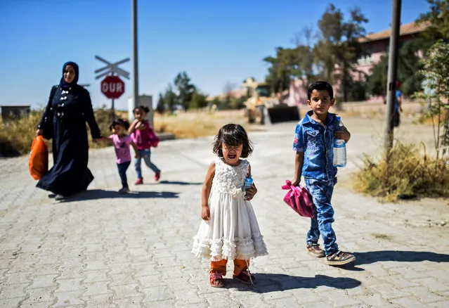Syrian refugees walk on their way back to the Syrian city of Jarabulus on September 7, 2016 at Karkamis crossing gate, in the southern region of Kilis, Turkey. (Photo by Bulent Kilic/AFP Photo)