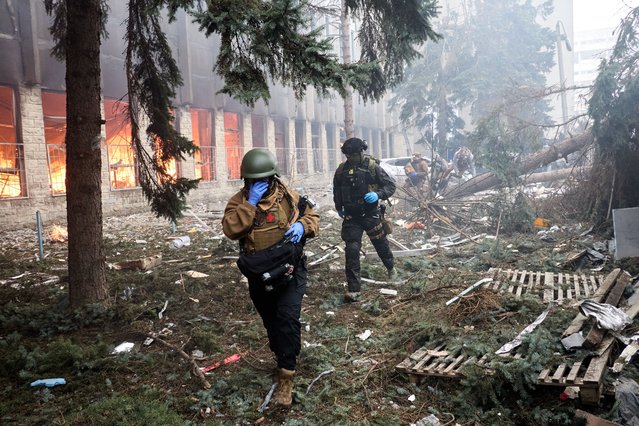 Ukrainian servicemen run near the site of a rocket attack on an industrial building in the Kholodnohirskyi district of Kharkiv, northeastern Ukraine, 20 March 2024, amid the Russian invasion. At least one person has died, and at least five others were injured after a Russian missile strike hit one of the districts of Kharkiv, the head of the Kharkiv military administration Oleh Syniehubov wrote on telegram, adding that people could be under the rubble. (Photo by Sergey Kozlov/EPA/EFE)