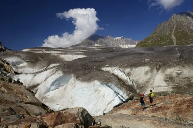 Hikers stand on the side of the Aletsch Glacier in Fiesch, Switzerland, August 12, 2015. (Photo by Denis Balibouse/Reuters)