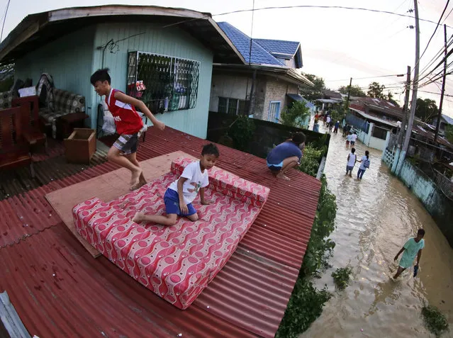 Filipino villagers take refuge on a roof of a house at a flooded village of Calumpit, Bulacan province, northern Philippines, 20 October 2015. Philippine disaster relief authorities warned of more floods from a powerful storm which was lingering over the country's northern region, Romina Marasigan, Philippines disaster relief agency spokewoman said. (Photo by Francis R. Malasig/EPA)