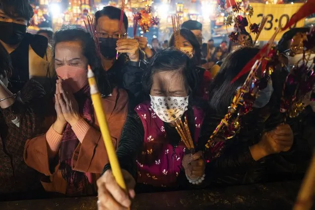 Worshippers wearing face masks burn their first joss sticks as they pray at the Wong Tai Sin Temple in Hong Kong, Saturday, January 21, 2023, to celebrate the Lunar New Year which marks the Year of the Rabbit in the Chinese zodiac. (Photo by Bertha Wang/AP Photo)