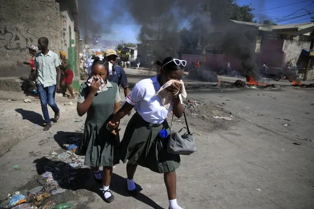 Students walk past a burning barricade that was set up by members of the police protesting bad police governance in Port-au-Prince, Haiti, Thursday, January 26, 2023. (Photo by Joseph Odelyn/AP Photo)