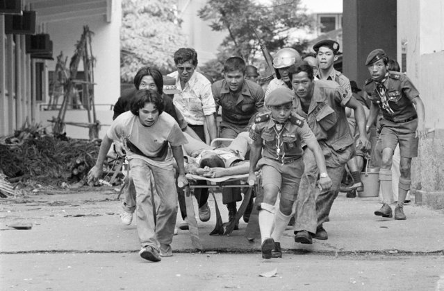 In this October 6, 1976 file photo, a wounded man is carried to an ambulance as authorities and leftist students trade fire on Thammasat University campus in Bangkok, Thailand. (Photo by Neal Ulevich/AP Photo)