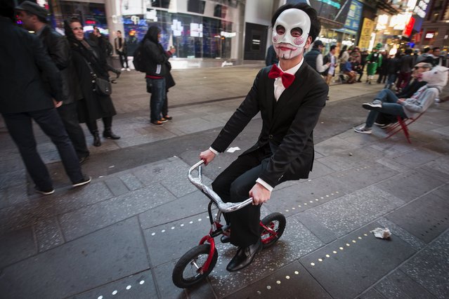 A man rides a tiny bicycle though Times Square on Halloween in the Manhattan borough of New York October 31, 2015. (Photo by Carlo Allegri/Reuters)
