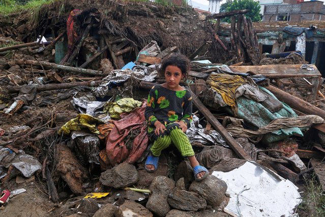 A girl sits on the rubble of her damaged home following flash flooding in the Pir Baba neighborhood in northwestern Pakistan, August 17, 2025. (Photo by Muhammad Sajjad/AP Photo)