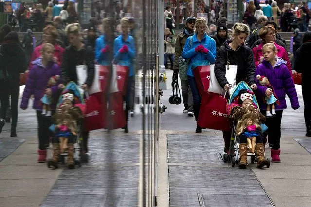 Shoppers are reflected in a window as they walk though Times Square in New York November 30, 2014. (Photo by Carlo Allegri/Reuters)