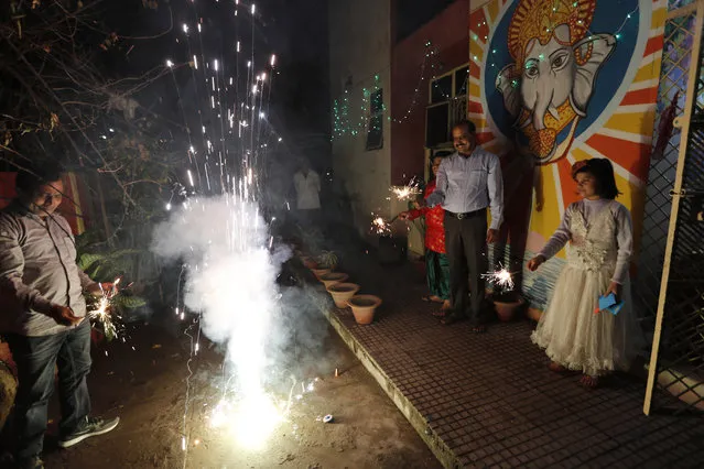 People play with fireworks during Diwali, the Hindu festival of lights, in Prayagraj, India, Saturday, November 14, 2020. Hindus across the country are celebrating Diwali where people decorate their homes with lights and burst fireworks. (Photo by Rajesh Kumar Singh/AP Photo)