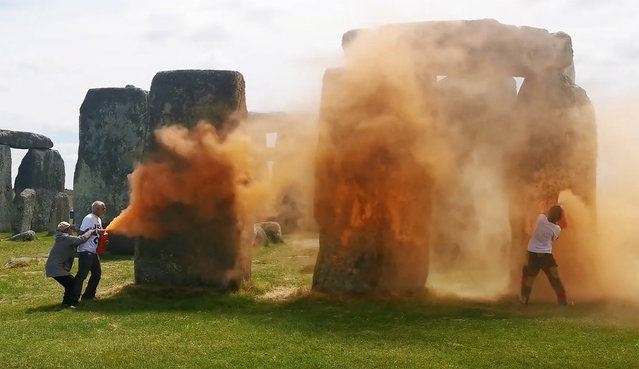An image grab from a video released by the Just Stop Oil climate campaign group shows activists spraying an orange substance at Stonehenge in Wiltshire, southwest England, on June 19, 2024. UK police said officers had arrested two people after environmental activists sprayed an orange substance on Stonehenge, the renowned prehistoric UNESCO World Heritage Site in southwest England. (Photo by Just Stop Oil/Handout via AFP Photo)