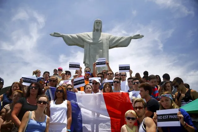 People hold placards and a French flag in front of the Christ the Redeemer statue, in tribute to the victims of Paris attacks, in Rio de Janeiro, Brazil, November 14, 2015. The placards read: "Rio is Paris". (Photo by Pilar Olivares/Reuters)
