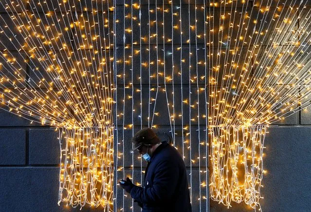 A man wearing a protective face mask amid the outbreak of the coronavirus disease (COVID-19) walks past a Christmas illumination in Kyiv, Ukraine on December 7, 2020. (Photo by Gleb Garanich/Reuters)