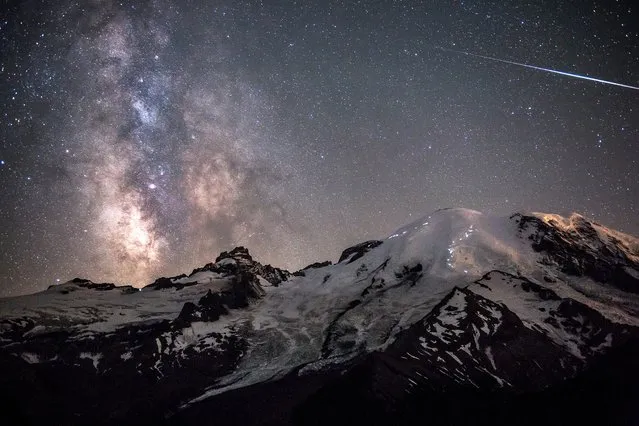 Ascent of Angels. A meteor can be seen piercing through the darkness as the Milky Way towers above the 4,392m peak of Mount Rainier in Washington, USA. The white lights dotted across the rocky paths of the mountain’s face are the headlamps of hikers ascending to the peak. (Photo by Brad Goldpaint)