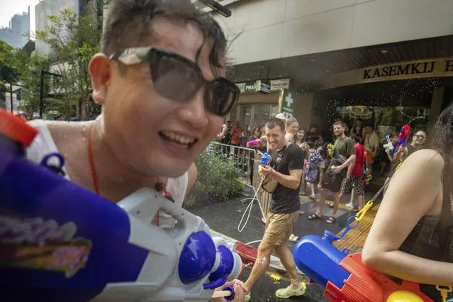 A tourist, center, spays water gun to celebrate Songkran festival in Prachinburi Province, east of Bangkok, Thursday, April 13, 2023. (Photo by Nava Sangthong/AP Photo)