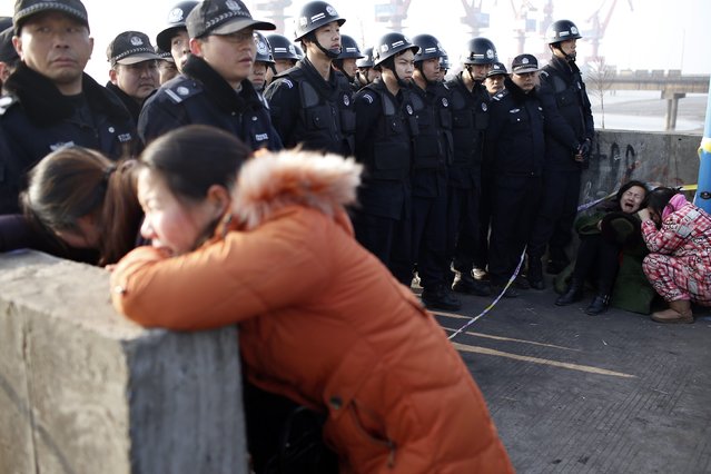 Relatives of a person missing after a tug boat sank, cry next to police officers on the bank of the Yangtze River, near Jingjiang, Jiangsu province January 17, 2015. (Photo by Aly Song/Reuters)