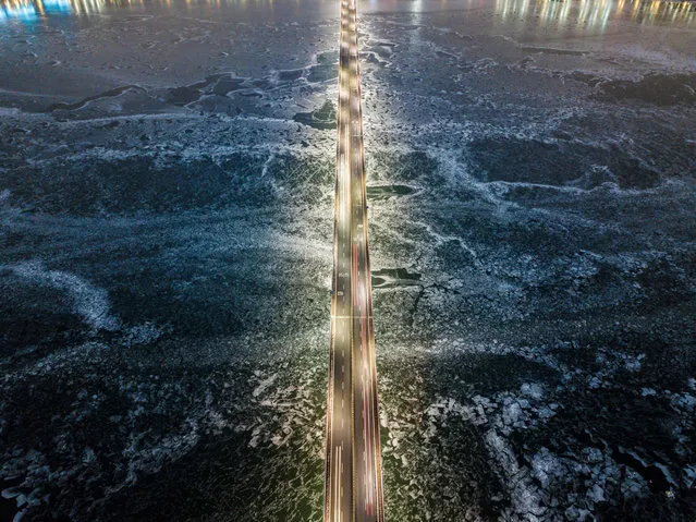 A photo taken on January 10, 2021 shows a general view of traffic passing over a bridge above the frozen Han river in Seoul. (Photo by Ed Jones/AFP Photo)