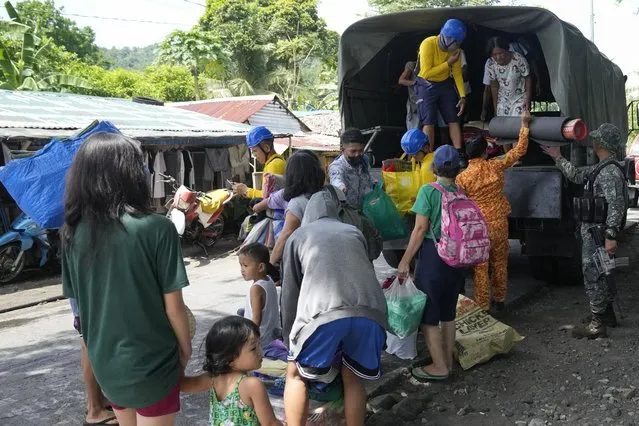 Residents are assisted as they come down from a military truck at an evacuation center in Santo Domingo town, Albay province, northeastern Philippines, Tuesday, June 13, 2023. (Photo by Aaron Favila/AP Photo)