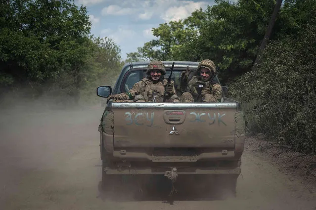 Ukrainian soldiers smile as they ride in a pickup van on the frontline near Bakhmut, the site of fierce battles with the Russian troops in the Donetsk region, Ukraine, Monday, June 5, 2023. Writing on the car reads UAF (Ukrainian Armed Forces). (Photo by Iryna Rybakova via AP Photo)