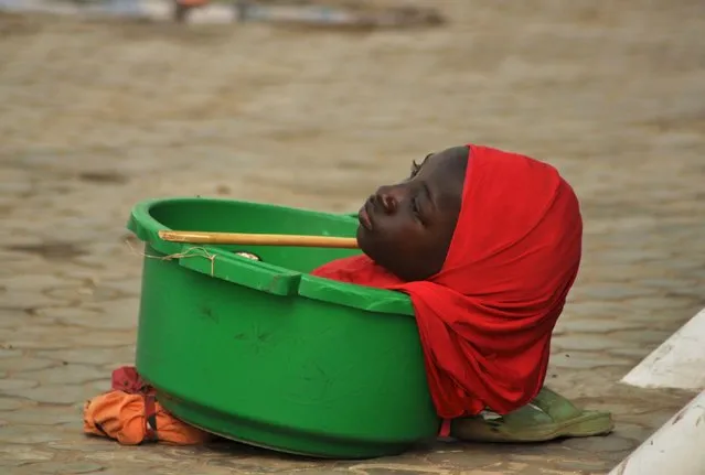 A physically challenged girl looks on she is kept in a basin to seek alms from people on the street in Kano, Nigeria December 30, 2015. The girl has suffered from her condition since birth. (Photo by Reuters/Stringer)