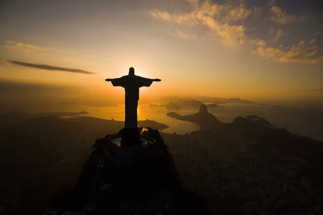 The sun rises behind the Christ the Redeemer statue, above the Guanabara bay in Rio de Janeiro, Brazil, Tuesday, July 19, 2016. With the Olympics set to start on Aug. 5, the games and the city have been overshadowed by security threats, violence, the Zika virus and a national political corruption scandal. (Photo by Felipe Dana/AP Photo)