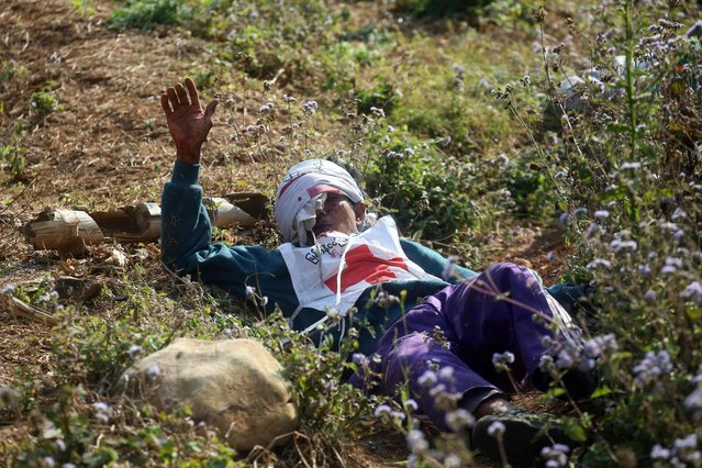 An injured Myanmar Red Cross volunteer lies on ground after vehicles of a rescue convoy were attacked by Kokang rebels nearthe  self-administered Kokang capital Laukkai, northern Shan State, Myanmar, on February 17, 2015. Myanmar's president has vowed “not to lose an inch” of territory in clashes with ethnic rebels in a region bordering China, state-backed media said on February 17, after intense fighting sent tens of thousands fleeing across the frontier. (Photo by AFP Photo/Stringer)
