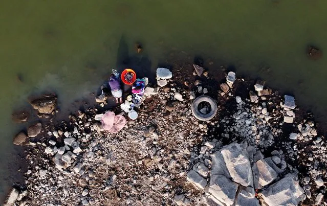 A woman washes clothes on the shore of Villa Victoria Dam, part of the Cutzamala System collecting water for distribution into Mexico City and the metropolitan area as it is running out of water as drought takes hold of the city of almost 22 million people, in Villa Victoria, State of Mexico, Mexico April 21, 2021. (Photo by Carlos Jasso/Reuters)