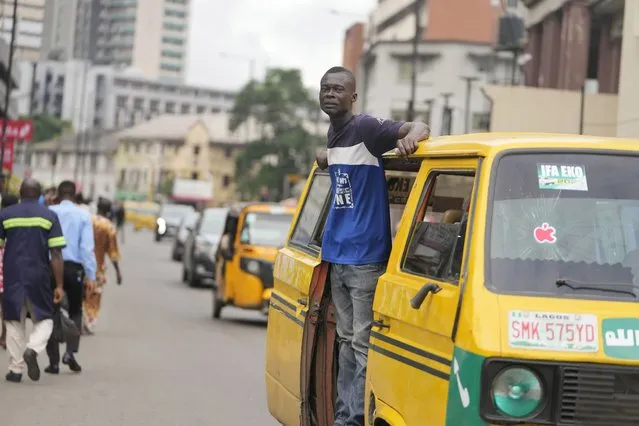 A commercial bus conductor calls for passengers on the streets of Lagos, Nigeria, Tuesday September 5, 2023. (Photo by Sunday Alamba/AP Photo)