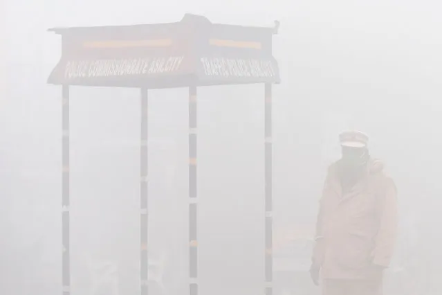 A policeman stands guard on a street amid dense fog on a cold winter morning in Amritsar on December 24, 2020. (Photo by Narinder Nanu/AFP Photo)