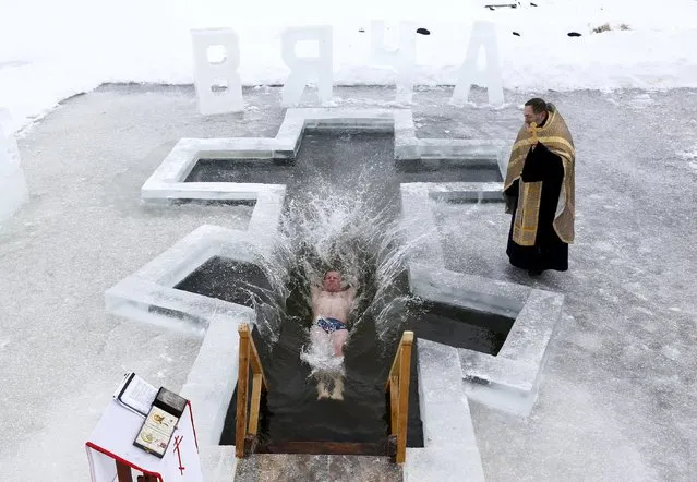 A man dips into the icy waters of a lake as part of celebrations for Orthodox Epiphany on the outskirts of Minsk, January 18, 2016. Orthodox believers will mark Epiphany on January 19 by immersing themselves in icy waters regardless of the weather. (Photo by Vasily Fedosenko/Reuters)