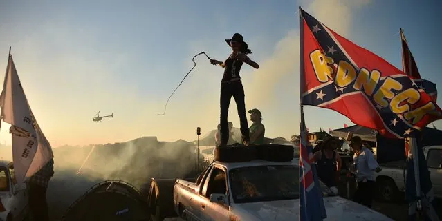 Photo taken on September 29, 2018 shows a reveller cracking a bull whip on top of her ute at the annual Deni Ute Muster in Deniliquin. Thousands of people flocked to the rural Australian town of Deniliquin in a rowdy celebration of their love of utility vehicles and the outback, with whip-cracking and bull-riding contests among the highlights. (Photo by Peter Parks/AFP Photo)