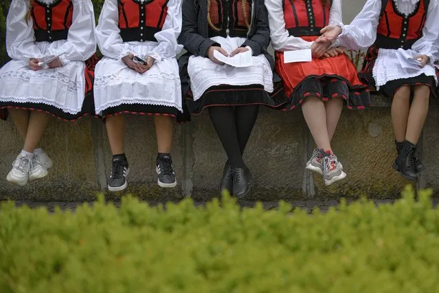 Girls wearing traditional outfits rest during a Catholic pilgrimage attended by tens of thousands who joined their faith's biggest religious event, in Sumuleu Ciuc, Romania, Saturday, May 22, 2021. (Photo by Andreea Alexandru/AP Photo)