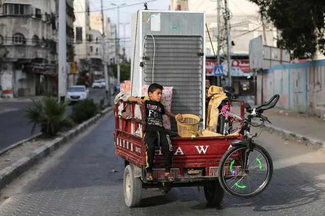 A Palestinian boy riding on an auto rickshaw loaded with his family's belongings heads to their home as he leaves a United Nations-run school where they took refuge during the recent cross-border violence between Palestinian militants and Israel, following Israel-Hamas truce, in Gaza on May 21, 2021. (Photo by Ibraheem Abu Mustafa/Reuters)