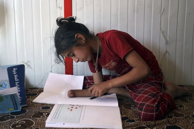 Doaa al-Hassan, 10 years old, who lost her hand to a cluster bomb in 2022, studies at a camp near the town of Ain Sheeb, northern Idlib province, Syria, on July 18, 2023. More than 300 people were killed by cluster munitions in Ukraine in 2022, according to an international watchdog, displacing Syria as the country with the highest number of deaths from the controversial weapons for the first time in a decade. (Photo by Omar Albam/AP Photo)