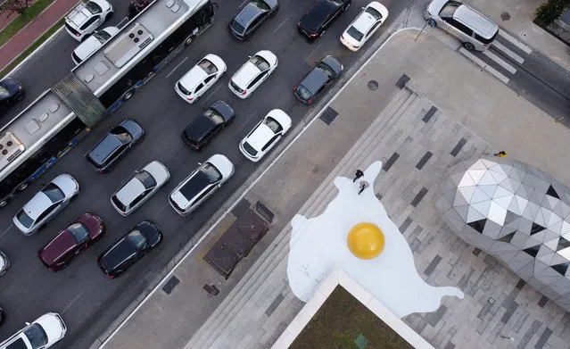 An aerial view shows cars on the street as the “Art Eggcident” installation by Dutch artist Henk Hofstra is seen on the sidewalk of Faria Lima Avenue, in Sao Paulo, Brazil on September 18, 2023. (Photo by Amanda Perobelli/Reuters)