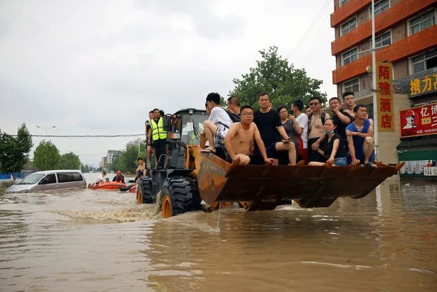 People ride a front loader as they make their way through a flooded road following heavy rainfall in Zhengzhou, Henan province, China on July 22, 2021. (Photo by Aly Song/Reuters)