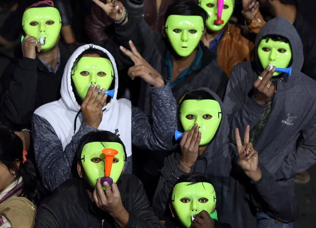 People wearing masks blow horns as they celebrate the New Year's countdown event in a road in Ahmedabad,  December 31, 2018. (Photo by Amit Dave/Reuters)