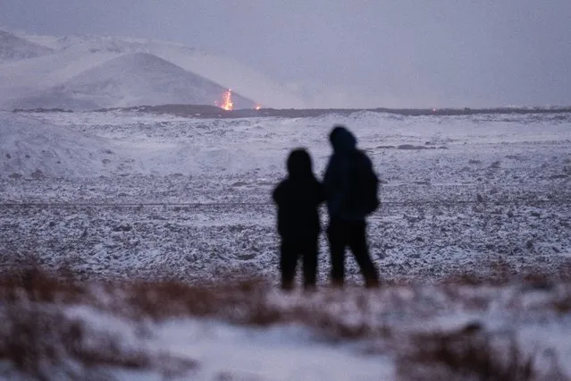Onlookers gather to watch the lava flow after a volcanic eruption near the town of Grindavik, Reykjanes peninsula, Iceland, 19 December 2023. The start of a volcanic eruption was announced by Iceland's Meteorological Office on 18 December night after weeks of intense earthquake activity in the area. (Photo by Anton Brink/EPA)