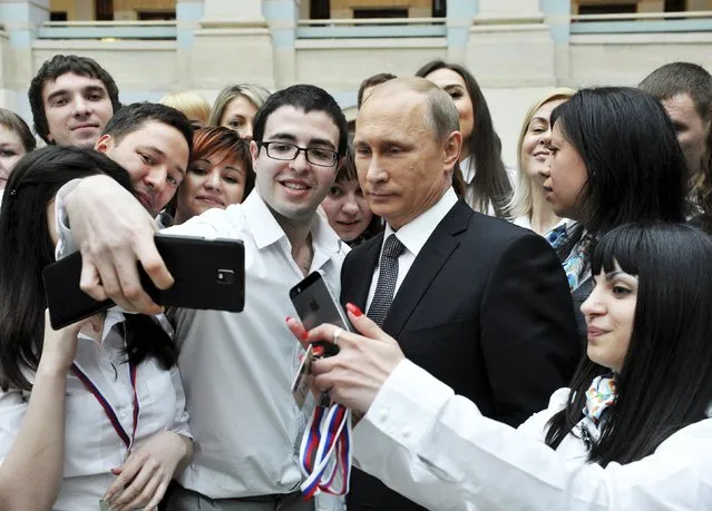 Russian President Vladimir Putin (3rd R, front) poses for a picture with call centre employees after a live broadcast nationwide call-in in Moscow April 16, 2015. (Photo by Mikhail Klimentyev/Reuters/RIA Novosti/Kremlin)