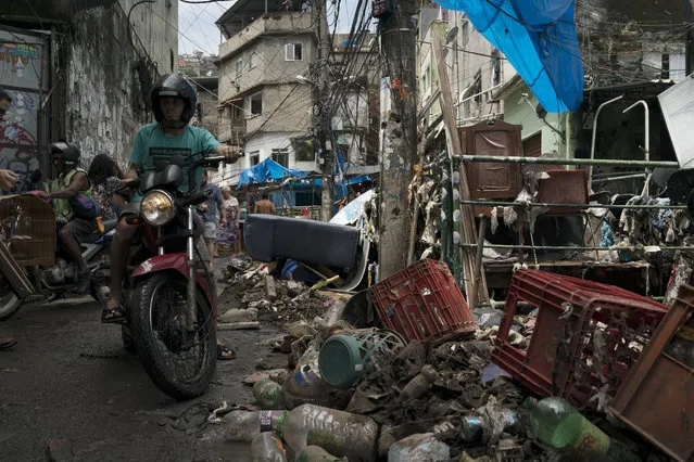 A man rides his motorcycle through an alley strewn with debris and mud in the aftermath of a violent storm in the Rocinha slum, in Rio de Janeiro, Brazil, Thursday, February 7, 2019. Rio officials say torrential downpours and strong winds have killed at least five people and left a trail of destruction. (Photo by Leo Correa/AP Photo)