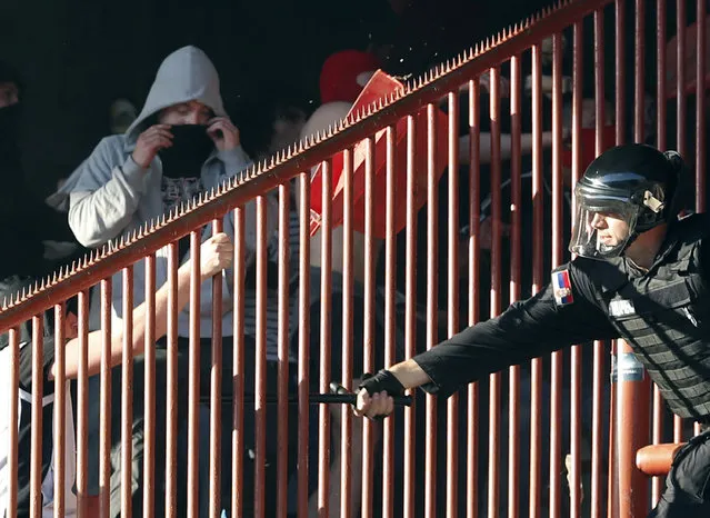 A Serbian riot police officer clashes with Red Star soccer fans during a Serbian National soccer league derby match between Red Star and Partizan, in Belgrade, Serbia, Saturday, April 25, 2015. (Photo by Darko Vojinovic/AP Photo)