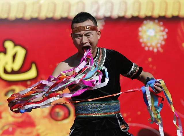 A man pulls ribbons from his mouth as he performs a feat of his strength during the opening of the temple fair for Chinese New Year celebrations at Ditan Park, also known as the Temple of Earth, in Beijing January 30, 2014. (Photo by Kim Kyung-Hoon/Reuters)