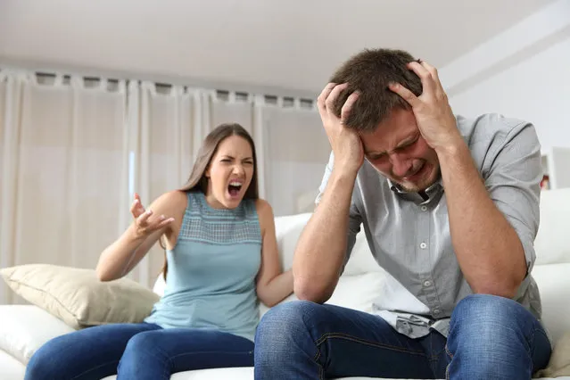 Couple arguing. Wife shouting to her desperate husband sitting on a couch in the living room at home. (Photo by Alamy Stock Photo)
