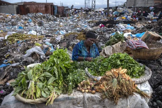 A woman selling greens waits for customers in the Croix des Bosalles market in Port-au-Prince, Haiti, Wednesday, September 22, 2021. The floor of the market is thick with decomposing trash and, in some places, small fires of burning trash. (Photo by Rodrigo Abd/AP Photo)