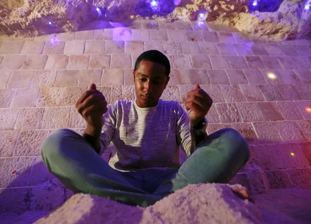A boy sits in the salt cave with salt in both hands during a session of meditation in Cairo, Egypt, November 14, 2016. (Photo by Mohamed Abd El Ghany/Reuters)