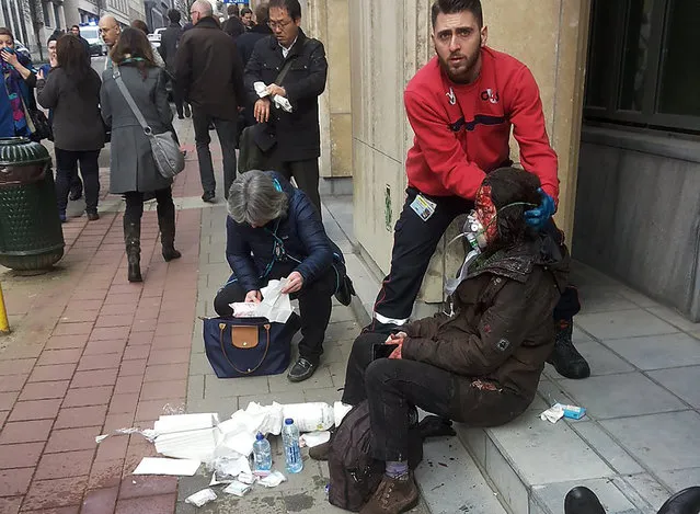 A private security guard helps a wounded women outside the Maalbeek metro station in Brussels on March 21, 2016 after a blast at this station located near the EU institutions. Belgian firefighters said at least 26 people had died after “enormous” blasts rocked Brussels airport and a city metro station today, as Belgium raised its terror threat to the maximum level. (Photo by Michael Villa/AFP Photo)