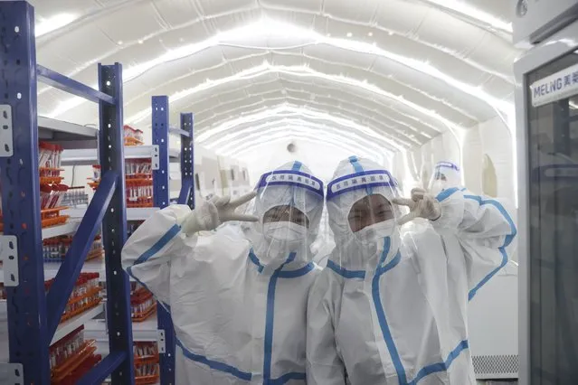 Medical workers who finished their daily work pose for a photo before leaving a mobile laboratory for nucleic acid test in Harbin, northeast China's Heilongjiang Province, November 5, 2021. A mobile, inflatable laboratory for conducting COVID-19 tests was officially put into use on Nov. 1 at a sports center in Harbin. The laboratory can cope with swab samples from 1.75 million people for nucleic acid tests per day. (Photo by Xinhua News Agency/Rex Features/Shutterstock)