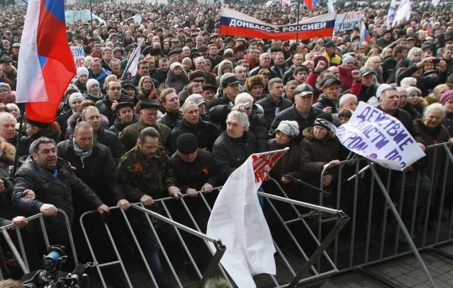 Pro-Russian activists hold Russian flags during a rally in center of Donetsk, Ukraine, Saturday, March 1, 2014. Supporters of new Ukrainian authorities and pro-Russia demonstrators clashed in Kharkiv and Donetsk a mostly Russian-speaking region in eastern Ukraine. Poster at right reads: “Donetsk with Russia”. (Photo by Sergey Vaganov/AP Photo)
