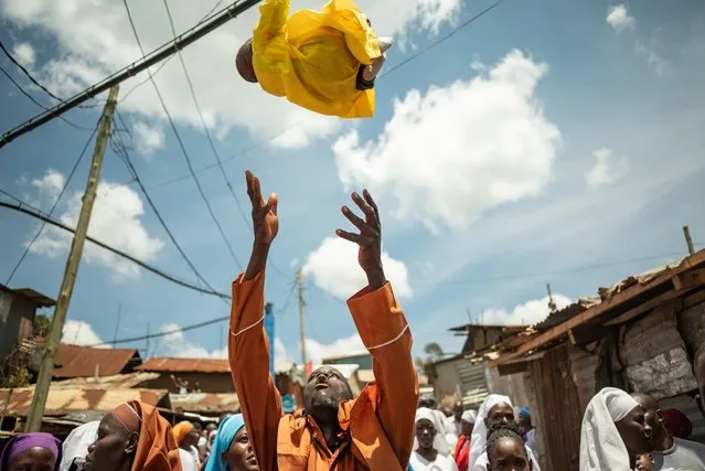 A member of the Africa Roho Msalaba church throws a 2 month old baby into the air during the “Throwing babies into the air” ritual in Kibera Slum of Nairobi, Kenya on March 10, 2024. The babies of the members of the Africa Roho Msalaba church, who are not taken out of the house until they are 2 months old and are not allowed to be seen by strangers, are introduced to the community by being paraded through the streets with the 'throwing babies in the air' ritual. (Photo by Edwin Ndeke/Anadolu via Getty Images)